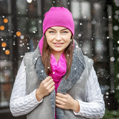 A happy woman walks around the city in winter. Pink hat and scar