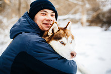 Man Walk With His Friend Red Siberian Husky Dog In Snowy Park. Toned