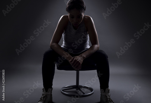 Fotografie, Obraz Silhouette of black female athelte sitting to rest or preparing for a competition or upset over losing and failing at sports