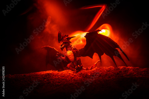 Obrazy smoki silhouette-of-fire-breathing-dragon-with-big-wings-on-a-dark-orange-background