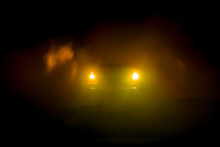 Silhouette Of Old Vintage Car In Dark Foggy Toned Background With Glowing Lights In Low Light.