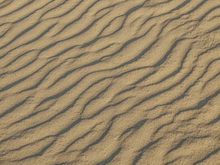 texture of sand waves on the beach or in the desert. the ripples of the sand is diagonal.