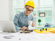 © Phushutter - Young Asian man architect working at working desk about his housing project.