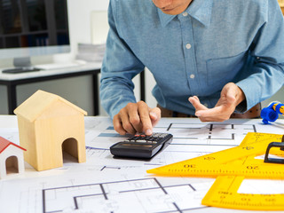 Young Asian man architect working at working desk about his housing project.