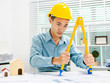 © Phushutter - Young Asian man architect working at working desk about his housing project.
