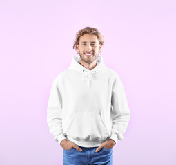 Wall Mural - Portrait of man in hoodie sweater on color background. Space for design