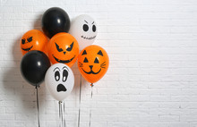 Color Balloons For Halloween Party Against White Brick Wall. Space For Text