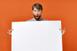 © SHOTPRIME STUDIO - surprised man holding white sheet of paper place free on red background