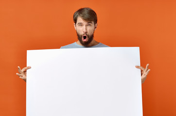 surprised man holding white sheet of paper place free on red background