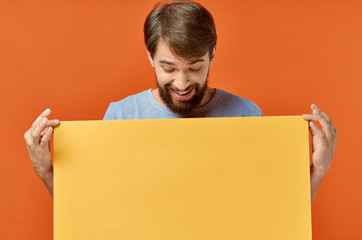 joyful man looks at empty yellow sheet of paper, free space