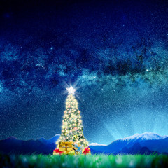 Wall Mural - Conceptual image of Decorated Christmas tree on green landscape over night sky with stars and galaxies.