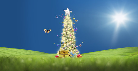Wall Mural - conceptual decorated shiny christmas tree on green landscape and flying butterflies over sunny clear