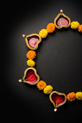 Diwali glowing Diya and flowers arranged in circular shape forming a design with copy space, selective focus