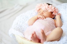 Sweet Newborn Caucasian Baby Sleeping. Pink Flower Head Band. New Born Child Photo Session.