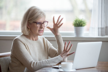 Angry stressed senior middle aged business woman annoyed with computer problem, old office worker hates stuck laptop, mad mature lady frustrated about bad online news, data loss, software failure