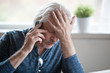 Frustrated older mature retired man feeling upset desperate talking on the phone having problems debt, stressed sad middle aged male depressed by hearing bad news during mobile conversation at home