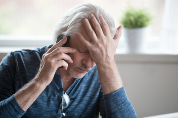 Frustrated older mature retired man feeling upset desperate talking on the phone having problems debt, stressed sad middle aged male depressed by hearing bad news during mobile conversation at home