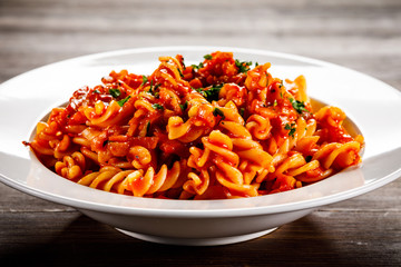 Pasta with tomato sauce and vegtables on wooden table