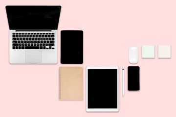 Flat lay photo of office table with laptop computer, digital tablet, mobile phone and accessories. on modern pink tone background. Desktop office mockup concept.