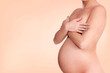 Naked pregnant woman posing against pastel background
