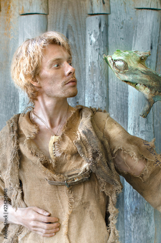 Fotografía young druid man in a suit from an old bag and looks at his strange staff with in