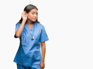 Wall Mural - Young arab doctor surgeon woman over isolated background smiling with hand over ear listening an hearing to rumor or gossip. Deafness concept.