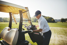 Senior Golfer Placing His Golf Club Bag Onto A Cart