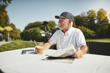 Smiling senior man relaxing at his golf club restaurant