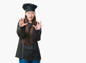 Poster - Young Chinese woman over isolated background wearing chef uniform afraid and terrified with fear expression stop gesture with hands, shouting in shock. Panic concept.