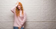 © Krakenimages.com - Young redhead woman standing over brick wall surprised with hand on head for mistake, remember error. Forgot, bad memory concept.