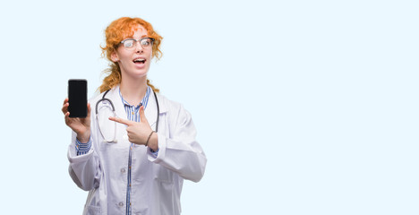 Poster - Young redhead doctor woman showing smartphone very happy pointing with hand and finger