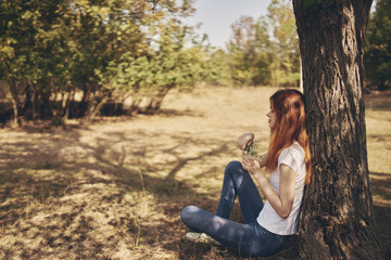 woman sitting on the ground leaning on a tree