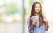 Young asian woman holding dollars over isolated background with surprise face pointing finger to himself