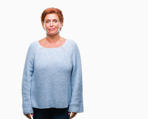 Canvas Print - Atrractive senior caucasian redhead woman wearing winter sweater over isolated background with serious expression on face. Simple and natural looking at the camera.