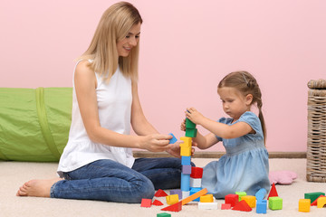 Poster - Young woman and cute girl playing with constructor on floor at home