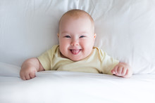 Top View Of Funny Little Baby Girl Lying On The Bed Under Blanket With Copy Space