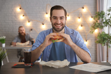 Man eating yummy burger in cafe