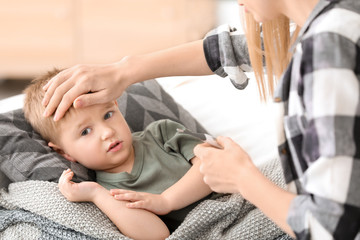 Mother measuring temperature of her sick son at home