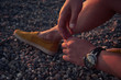 © ILIA - Close-up arms and leg of a man sitting on a pebble beach at sunset. Outdoor recreation. Lifestyle concept.