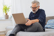 © contrastwerkstatt - älterer mann sitzt auf der couch und arbeitet am laptop