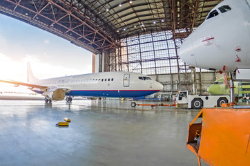 Passenger plane with a damaged engine is push roll up tow tractor to the hangar for repair, maintenance.