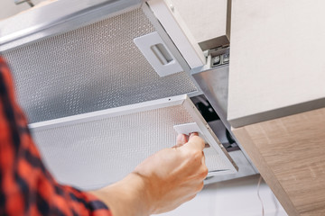 Wall Mural - Man repairs hood in kitchen. Replacement filter in cooker hood