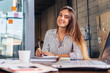 © undrey - Portrait of smiling female student writing looking at camera sitting at table