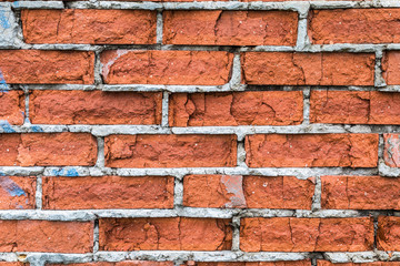 The old building wall of red bricks with cracks, clefts, chips and the parts of plaster