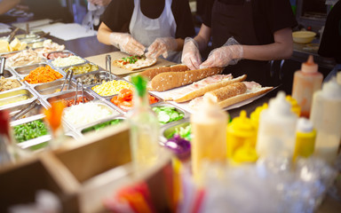 female street vendor hands making sandwich outdoors. cuisine snacks, cooking fast food for commercia