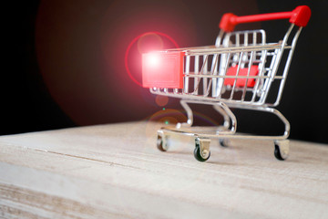 Mini shopping trolley in the supermarket stands on a wooden base and on a black background