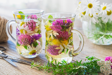 Wall Mural - Two glass cups of healthy herbal tea. Medicinal herbs on table.