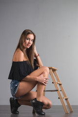 Wall Mural - Young beautiful woman teenager in a black top and torn denim shorts