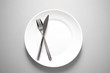© bidala - metal knife and fork on clean white plate for restaurant or food meal serving with grey background