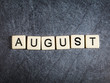 Letter tiles on black slate background spelling August